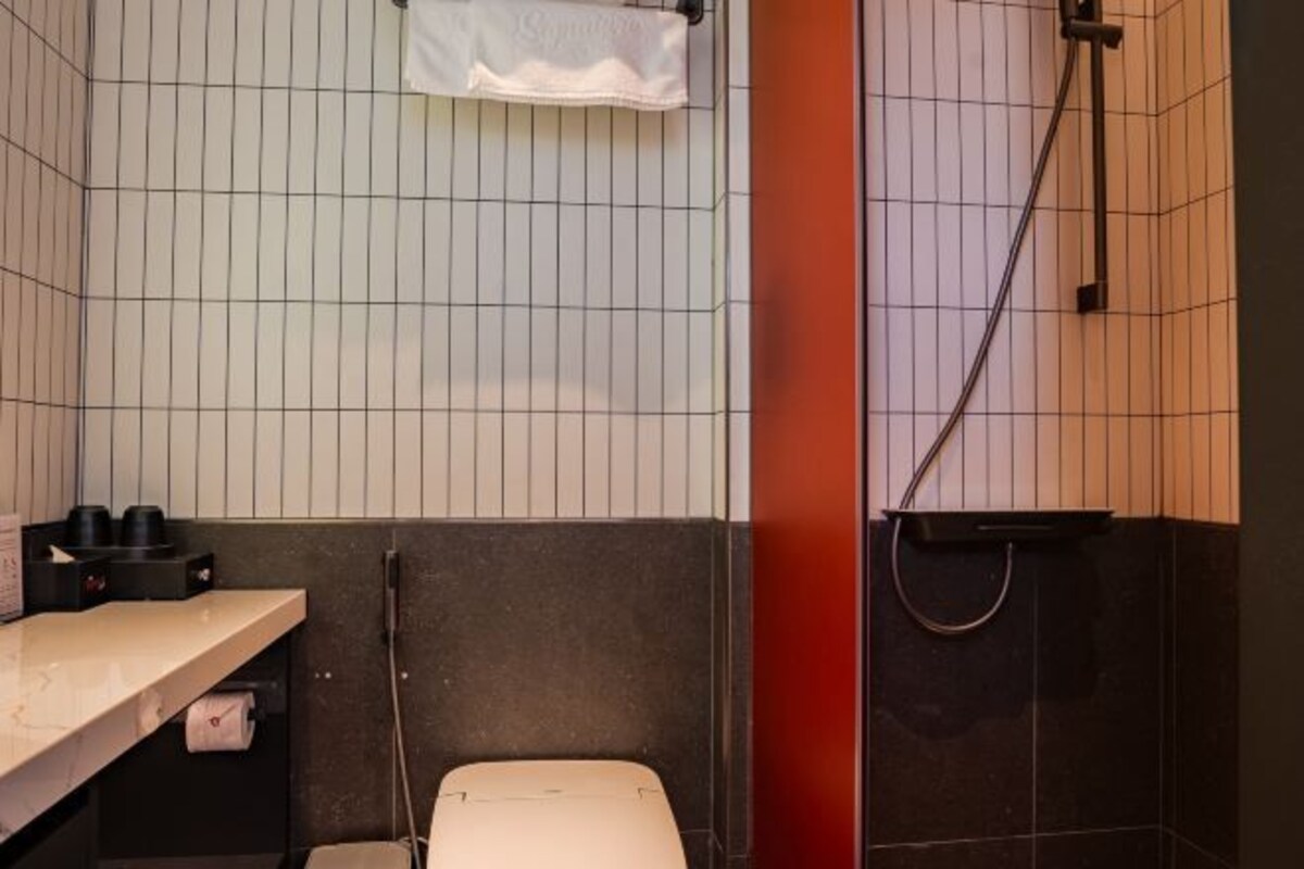 A small, tiled bathroom with a toilet, a sink, and a shower.