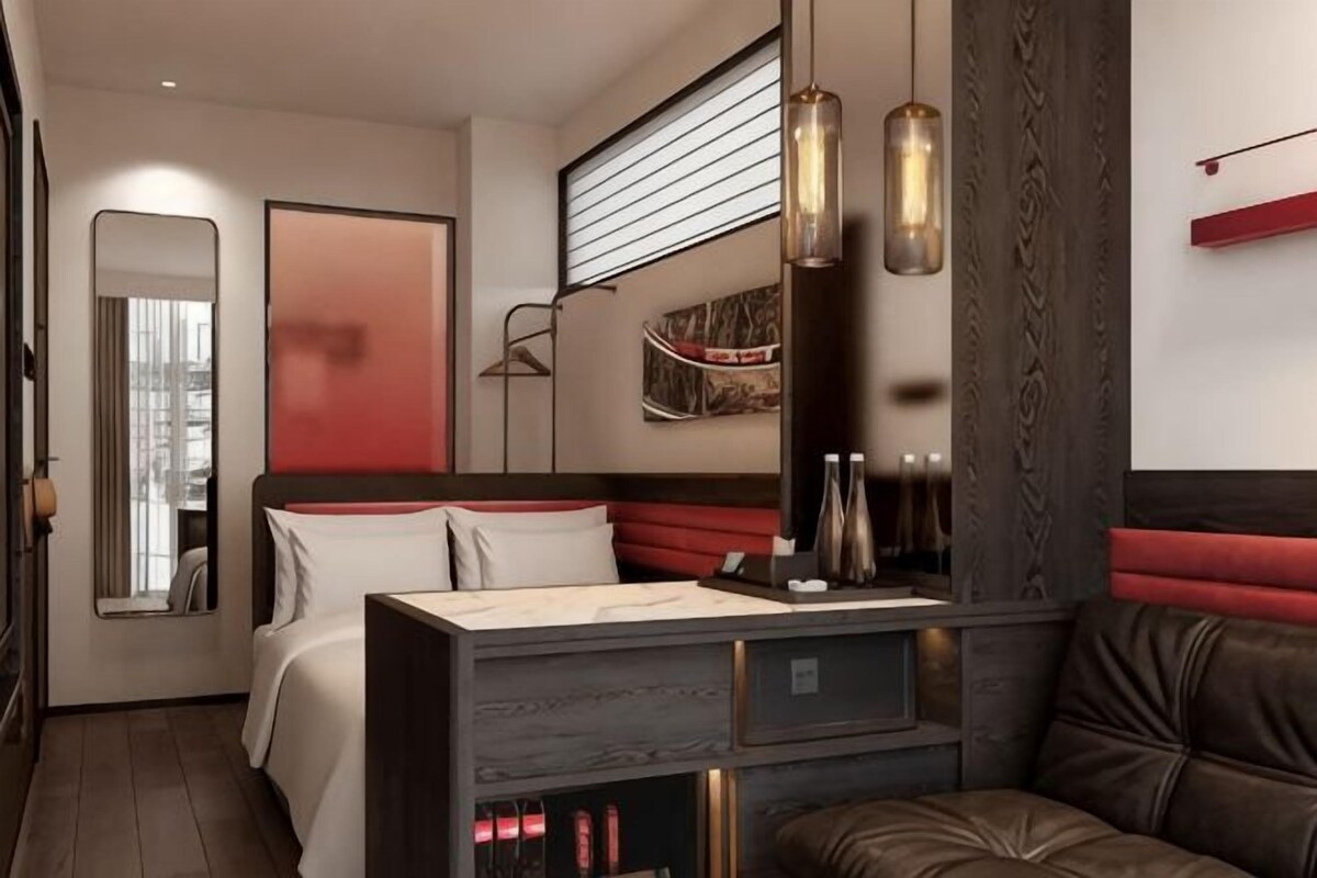 A modern hotel room with a bed, a desk, and a seating area.