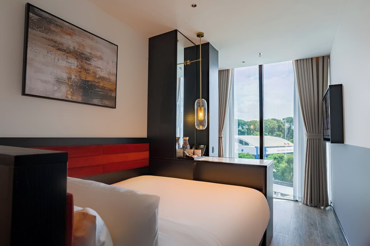 Ein modernes Hotelzimmer mit einem großen Bett, einer roten Akzentwand, einem großen Fenster mit Blick und einem wandmontierten Fernseher.