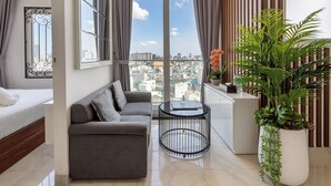A modern living room with a grey sofa, a round coffee table, and a large window with curtains.