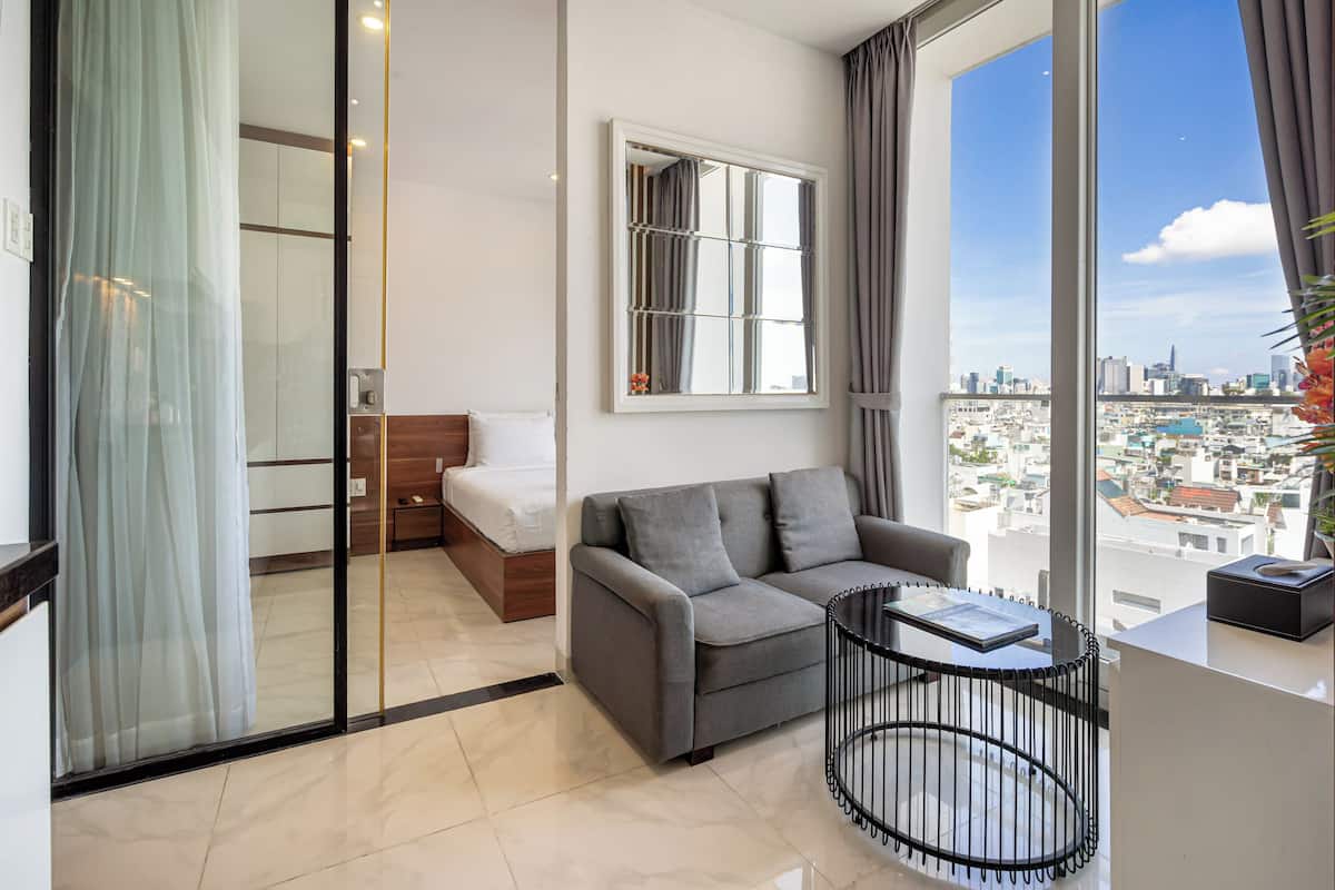 Una habitación de hotel moderna con balcón, sofá, una mesita y una cama.