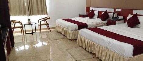 A hotel room with two beds, a small table, and chairs.