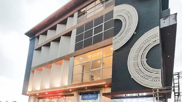 A modern building with a large entrance, a sign reading "SAKET GREENS," and a tiled walkway leading to the entrance. - Shubh Shaleen Springs by Nexottel (Bhopal)