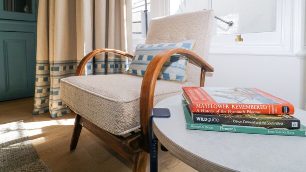 Una habitación acogedora con una silla de madera, una mesita y una ventana con cortinas.