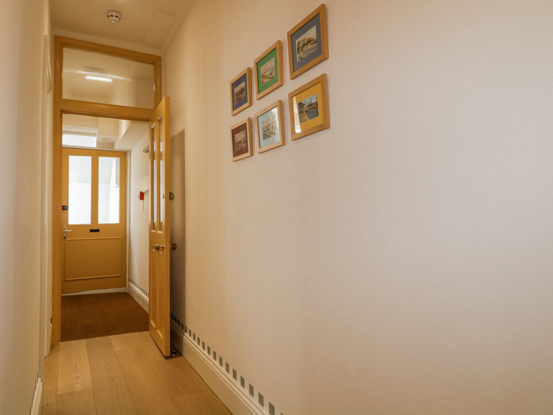 Ein Flur mit einer Holztür, einem Heizkörper und mehreren gerahmten Bildern an der Wand.