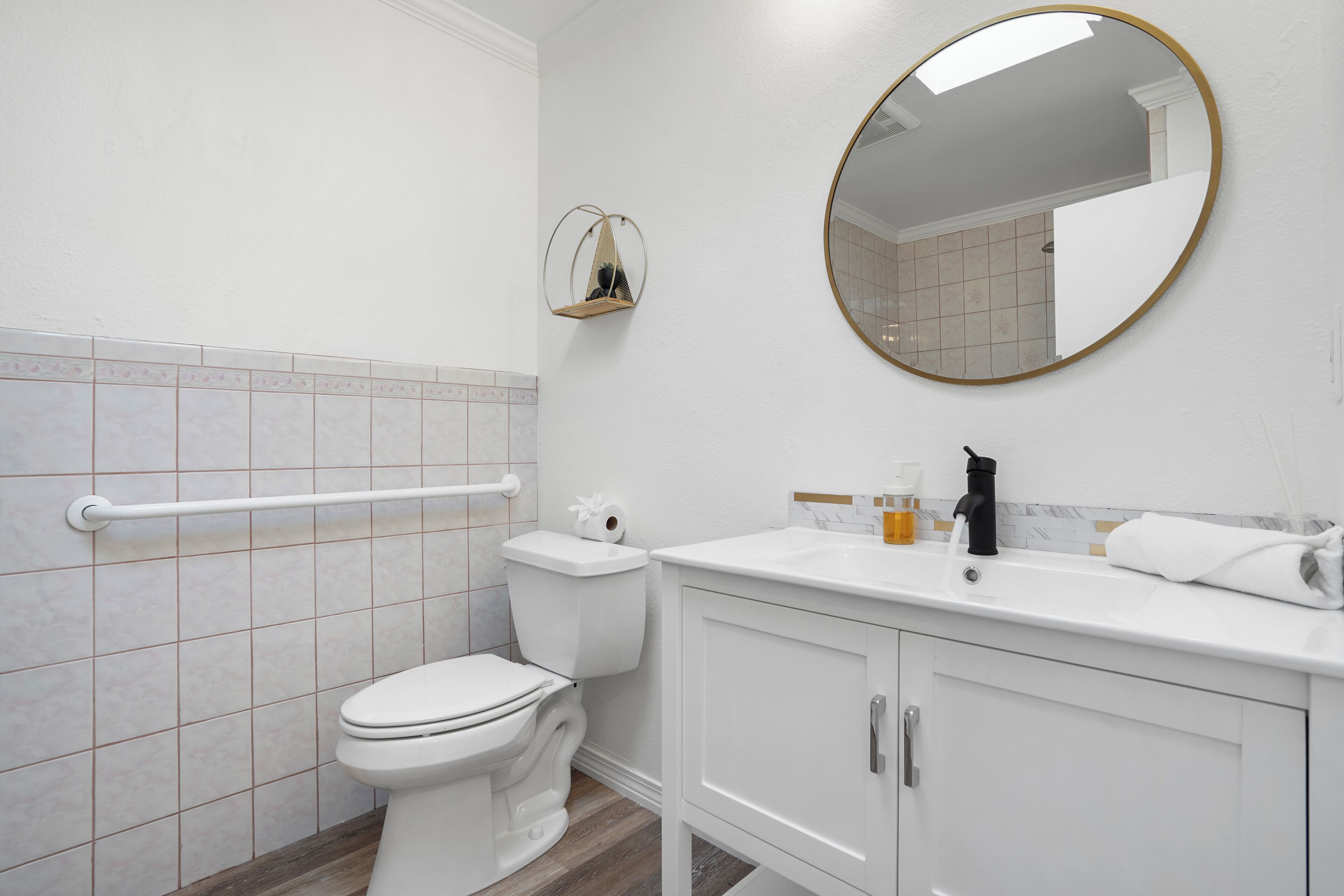 A bathroom with a toilet, a sink, a mirror, and a towel rack.