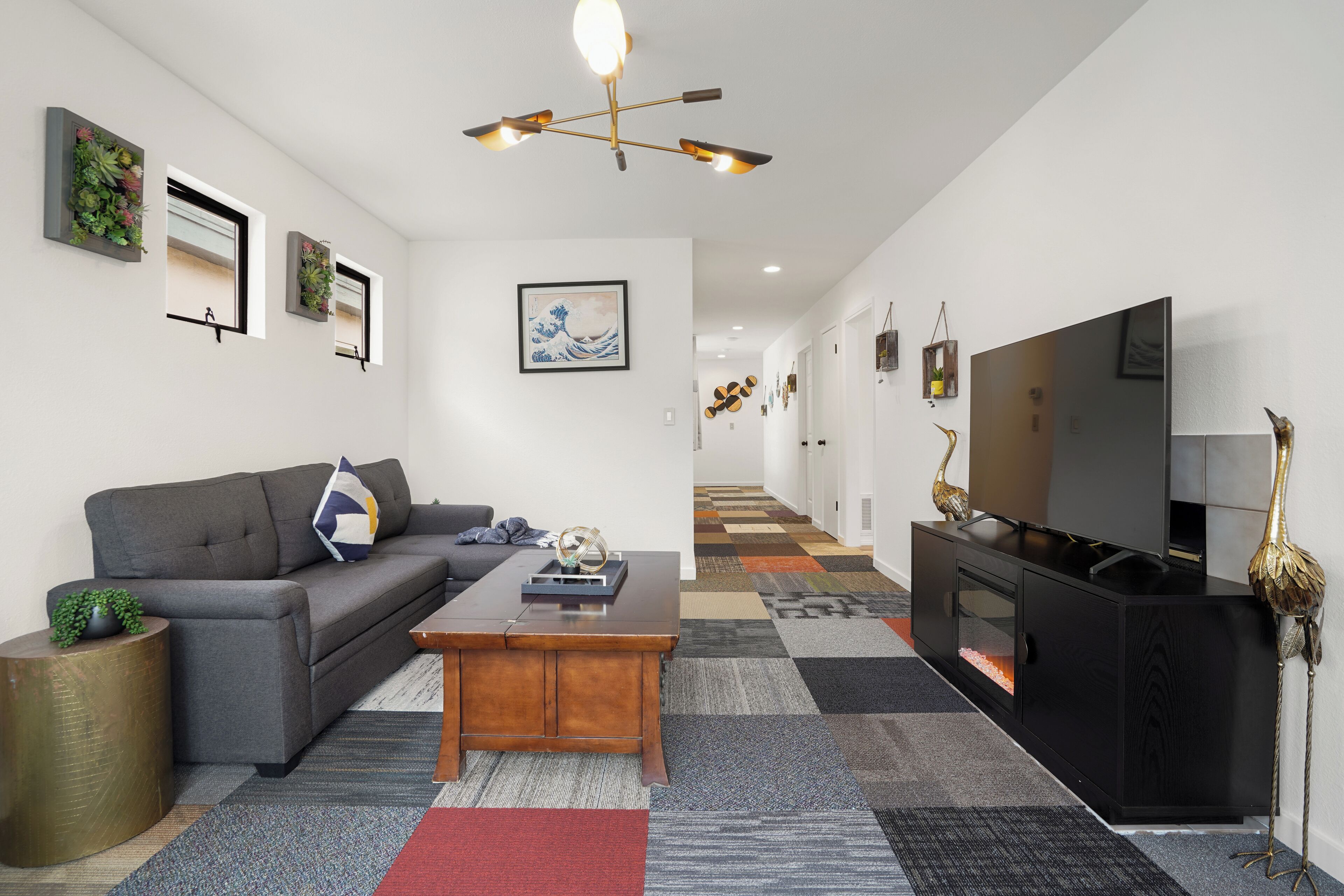A modern living room with a grey sofa, wooden coffee table, and a black entertainment unit with a flat-screen TV.