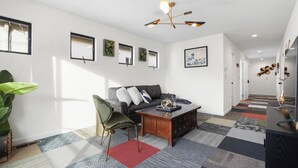 A modern living room with a sofa, coffee table, and a large plant. - 4Beds Private Unit Near BeachWalk Golf (Pacifica)