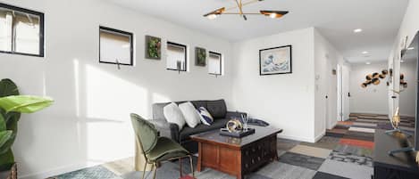 En moderne stue med sofa, sofabord og en stor plante.