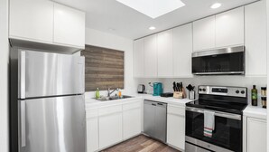 A modern kitchen with white cabinets, stainless steel appliances, a dishwasher, a microwave, and an oven. - 4Beds Private Unit Near BeachWalk Golf (Pacifica)