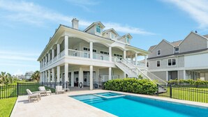 Une grande maison à plusieurs étages, dotée d’une piscine, d’un espace extérieur aménagé et d’une pelouse bien entretenue.
