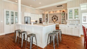 Une cuisine spacieuse dotée d’un îlot central, de tabourets de bar et de meubles de rangement intégrés.