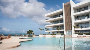A modern hotel with a pool, lounge chairs, and a view of the ocean. - Stylish 2BR Steps to Shore One Mambo 4 by Bocobay (Willemstad)