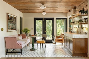 A cozy living room with a sofa, a coffee table, and a chair. There is a kitchen area with a sink and cabinets. - The Carly Fern Lodge | Luxe Wine Country Experience, Entire Lake, Trails & 21 Gorgeous Acres (Carlton)