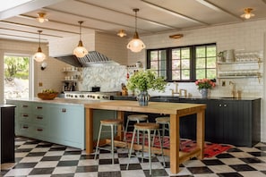 Une cuisine dotée d’un îlot central, de tabourets de bar, d’une cuisinière et de luminaires suspendus.