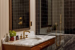 Ein Badezimmer mit Marmorwaschbecken, goldenen Armaturen und einer Duschkabine aus Glas.