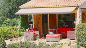 A house with a covered patio, wicker furniture, and a garden.