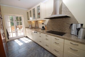 A kitchen with a granite countertop, stainless steel appliances, and a view through a glass door to an outdoor area.