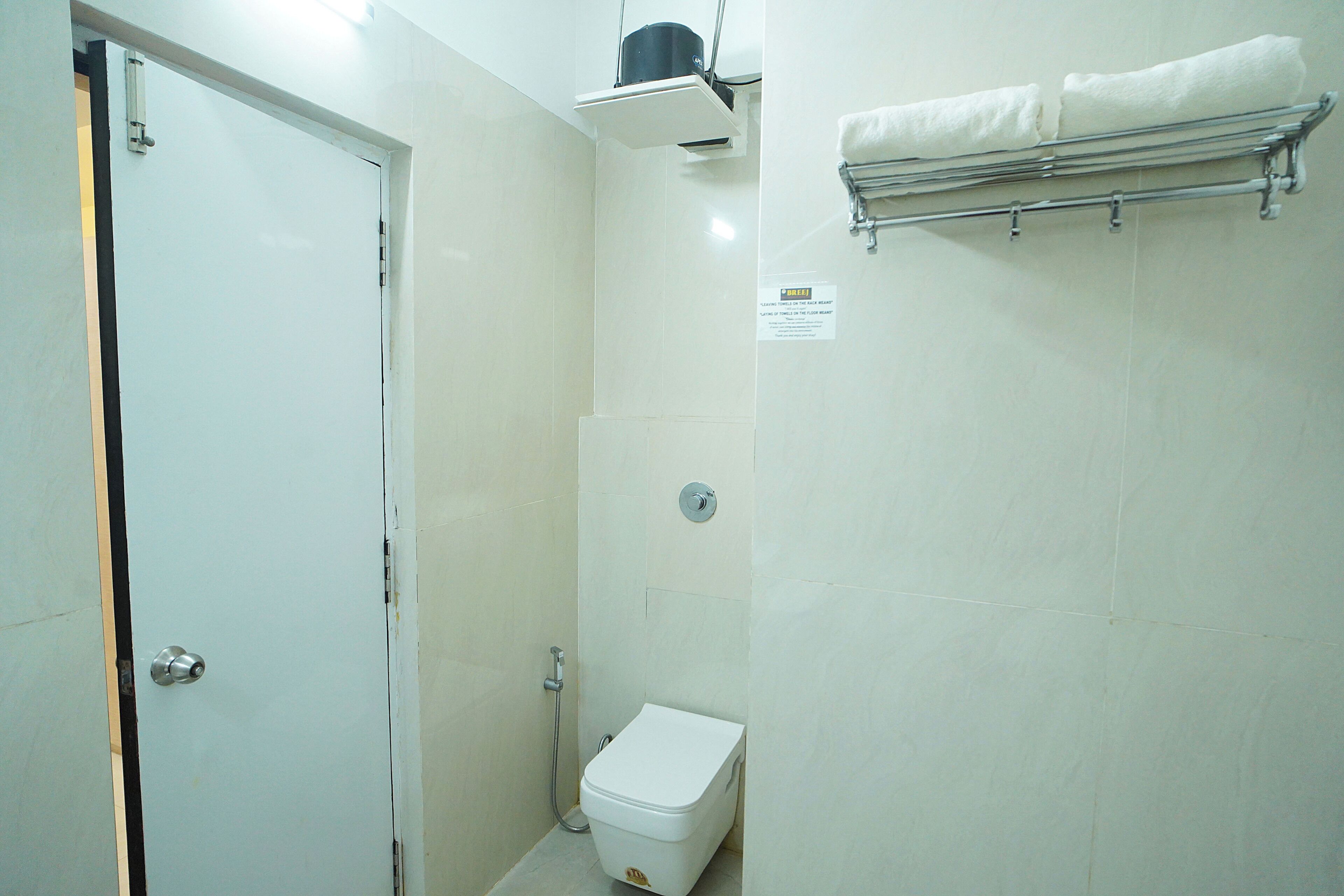 Een badkamer met een toilet, een douche en een handdoekhouder.
