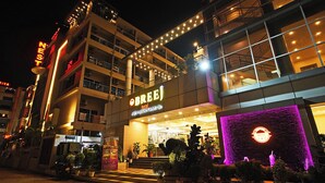 Un hotel con un letrero llamativo, plantas en macetas exteriores y una entrada bien iluminada.