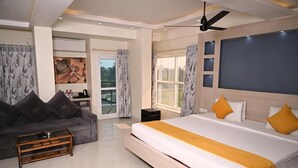 Un dormitorio moderno con una cama grande, un sofá, un ventilador de techo y vistas al exterior.