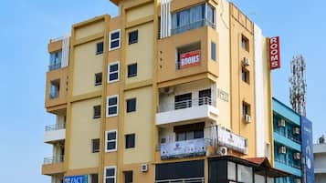 Un hotel de varios pisos con un cartel llamativo que anuncia habitaciones y un restaurante en el piso superior.