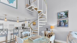 A modern kitchen with white cabinets, a glass dining table, and a spiral staircase. - 518 Seascape | Waterfront Views + Community Pool (Isle Of Palms)