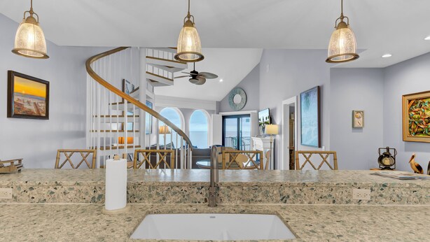 A modern kitchen with a granite countertop, a built-in sink, and pendant lighting. - 518 Seascape | Waterfront Views + Community Pool (Isle Of Palms)