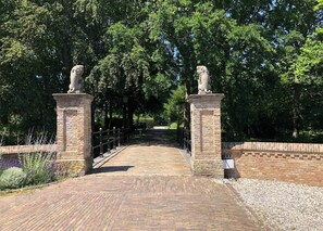 Walk across the stone bridge, flanked by majestic lion statues, to a serene pathway surrounded by lush greenery.