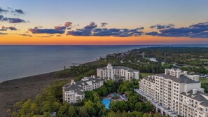 A resort with multiple buildings, a swimming pool, and a view of the ocean at sunset. - Serene Studio at Sandestin | Pool, Hot Tub, Beach Shuttle, Walk to Baytowne (Miramar Beach)