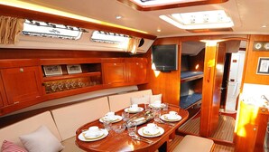Interior de barco con comedor, asientos y cocina.