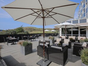 Relax in style with comfortable seating and lush greenery surrounding a central dining table.