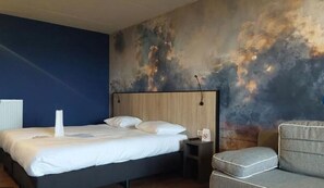 Relax in a spacious room with a large bed and comfortable sofa, set against a textured wall.
