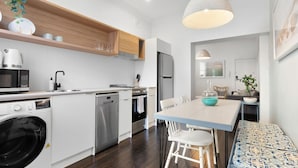 Una cocina moderna con lavavajillas, horno y microondas. Hay una mesa de comedor con sillas y un banco.