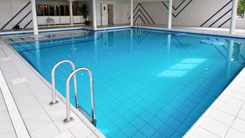Swimmers can enjoy a refreshing dip in this indoor pool surrounded by a geometric ceiling and windows.