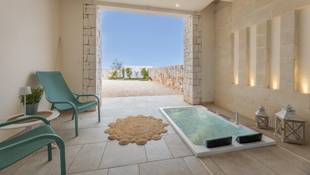 Een wellnessruimte met een bubbelbad, lounge stoelen en uitzicht op het strand.