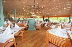 Enjoy a formal dining experience at this inviting restaurant, where wooden tables and chairs are set with white linens and fine cutlery.
