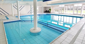 Relax by the pool surrounded by a blue and white tile floor and striped walls.