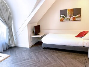 Relax in a stylish room with a large bed, flat-screen TV, and a beautiful painting above.