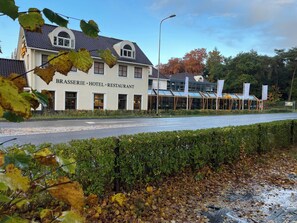 Classic hotel exterior with arched window and tiled roof, set amidst lush greenery and trees.