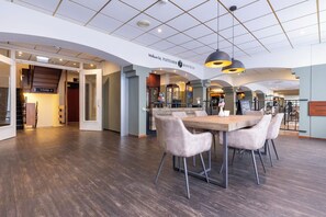 Welcome to FLETCHER HOTELS, where a modern lobby awaits with a high ceiling, reception desk, and casual dining area.
