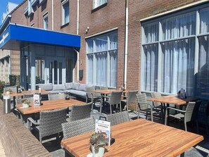 Guests can dine or socialize in this outdoor seating area with tables and wicker chairs.