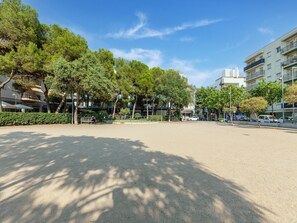 Una plaza abierta con árboles, cielo despejado y edificios al fondo.