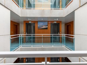 A modern building with two elevators, a glass railing, and a view of a coastal landscape. - Apartment in Palamós near the Beach (Palamos)