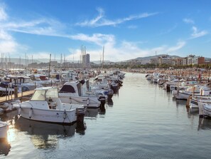 Un puerto deportivo con numerosas embarcaciones amarradas, cielo despejado y edificios al fondo.