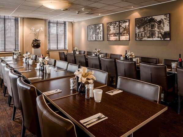Meetings and events are hosted in this sophisticated conference room, equipped with U-shaped tables, high-backed chairs, and a projector for presentations.