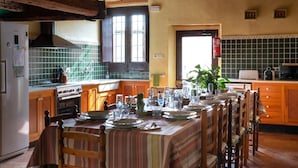 Une cuisine avec une table à manger pour six personnes, des meubles de rangement en bois, une cuisinière et un dosseret carrelé.