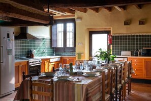 Cuina amb una taula de dinar preparada per a sis, armaris de fusta, una placa de cocció i un frontó de rajola.