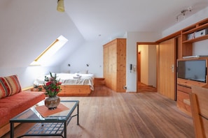 Ein modernes Schlafzimmer mit Oberlicht, einem Bett, einem Fernseher und Holzmöbeln.
