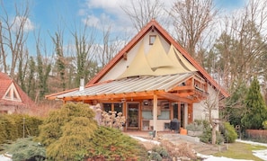 Ein Haus mit geneigtem Dach, einer Veranda und einem kleinen Garten.